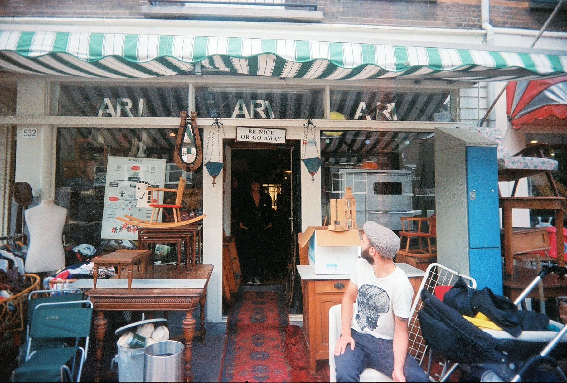 antique storefront with sign above door that reads be nice or go away