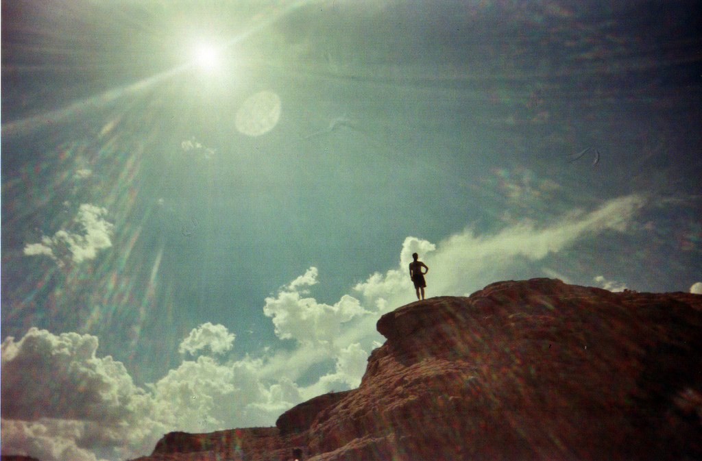 person preparing to recreationally jump from a cliff into a lake