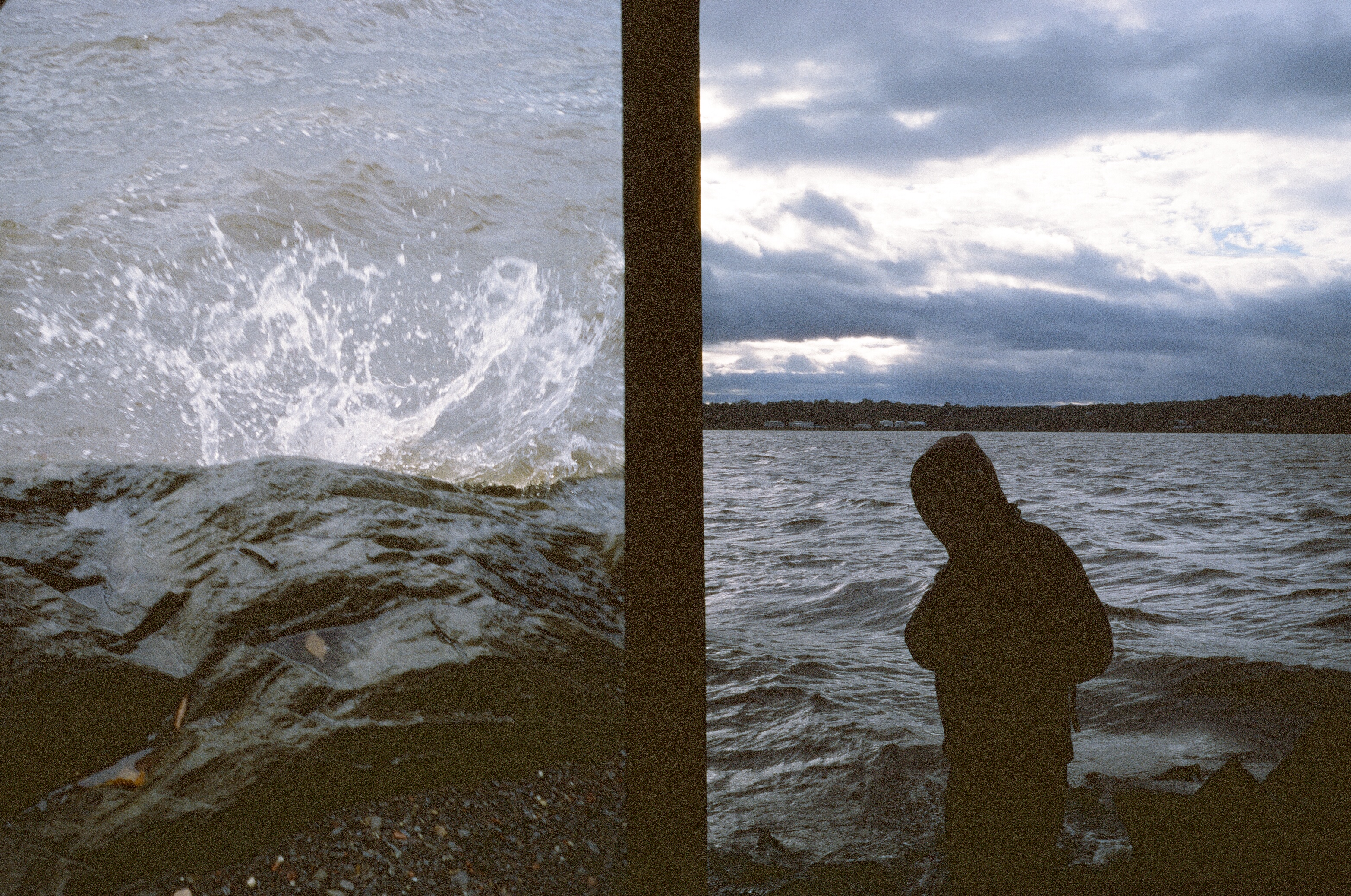 water splashes on rocks someone wearing a hood stands at river's edge