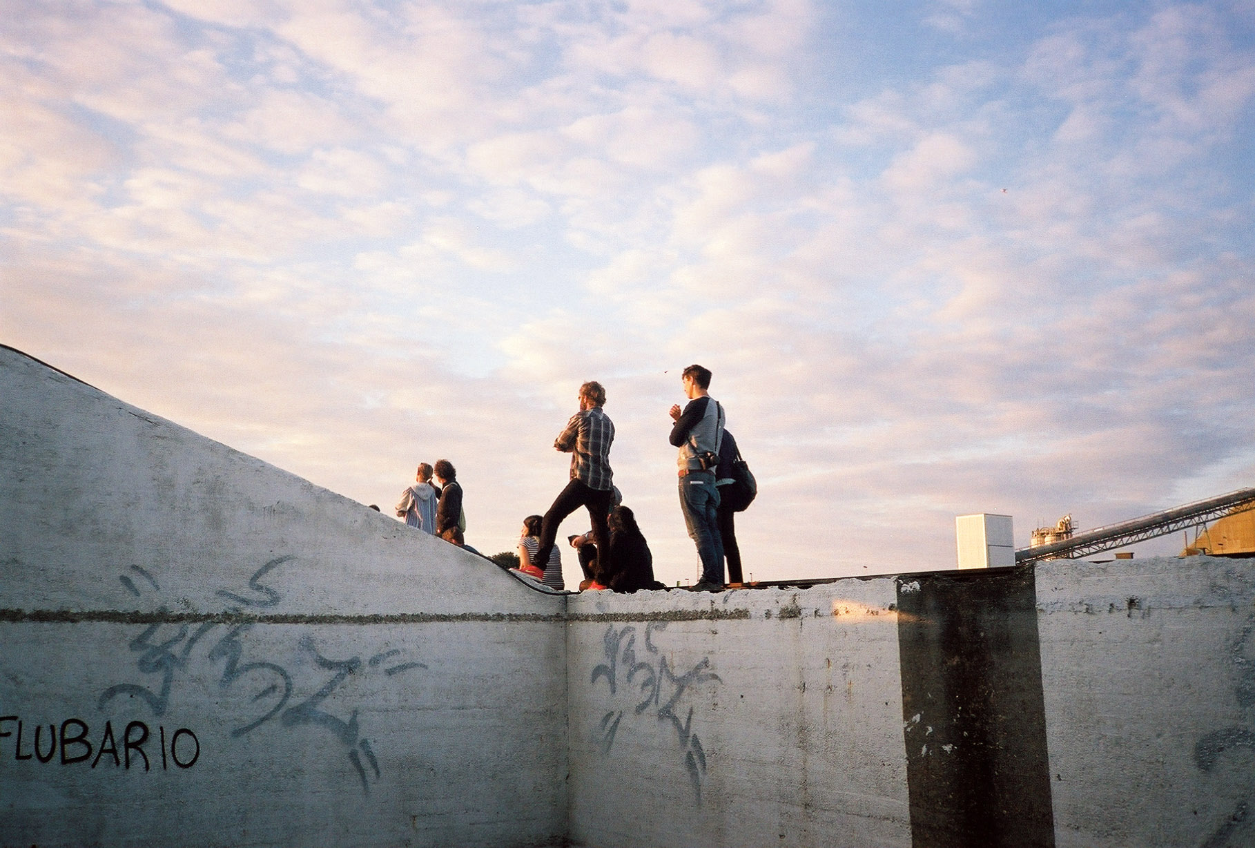 group of people standing on a wall to watch a band play